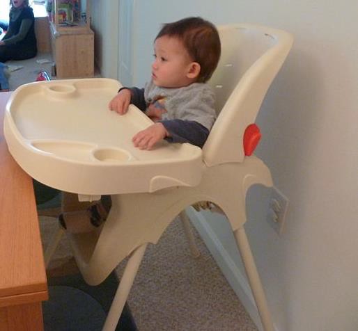 An infant sitting in a highchair.