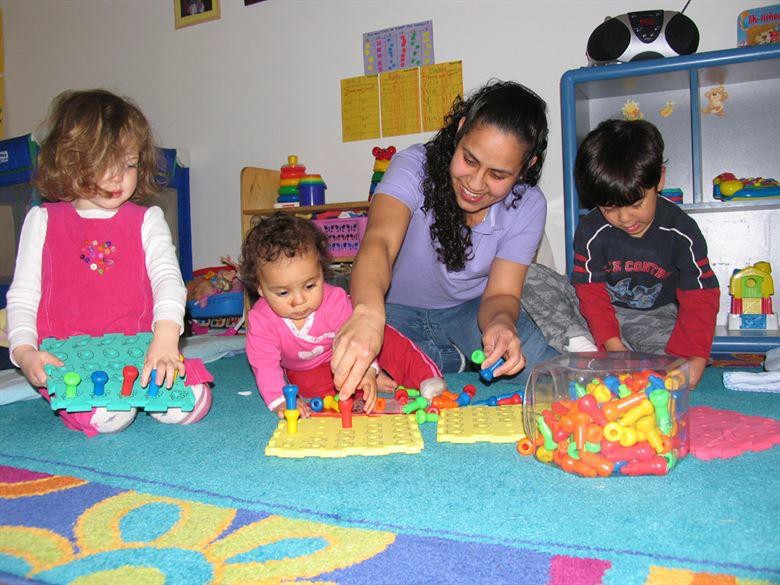 A caretaker playing with a group of children.